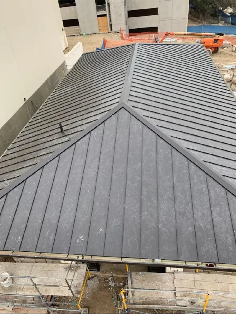 Commercial metal roof construction with crane equipment in Harvest